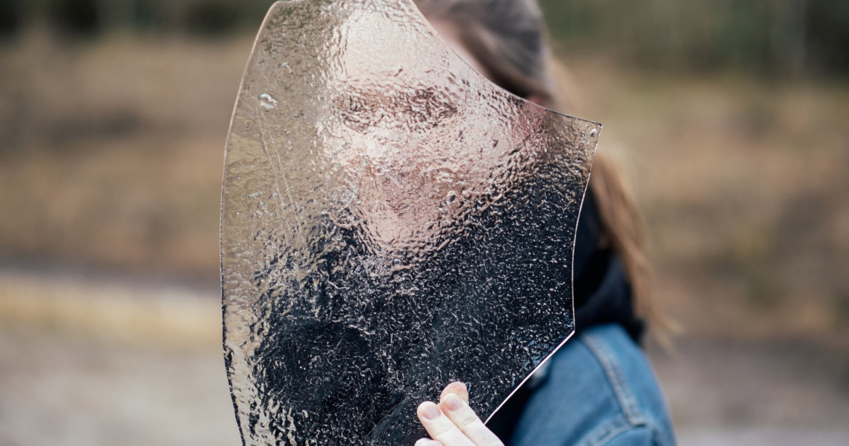a person covering face with frosted glass